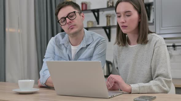 Serious Young Couple Working on Laptop in Living Room 