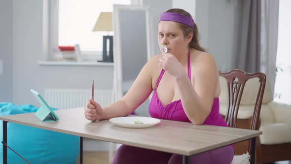 Depressed Overweight Woman Looking at Cucumber Slices in Plate Sighing