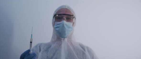 Woman lifting up a full syringe with fluid facing the camera slow motion