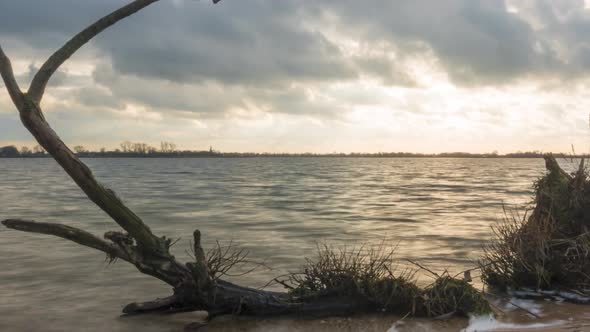 Tree trunk washed ashore, time lapse of waves on beach, slider shot