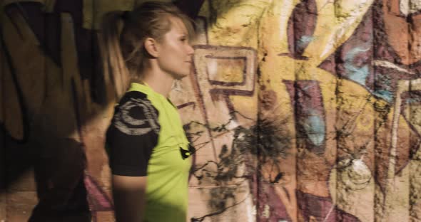 Young Blond Woman in Fitness Wear Walking Near Grunge Graffiti Wall