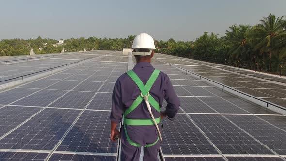 Construction Worker Walks on a Solar Panel Roof