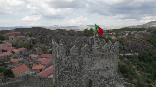 Portuguese Flag at Hilltop towering castle of Sortelha, Portugal. Orbiting shot