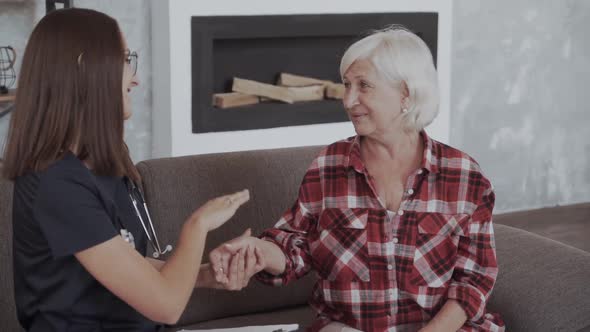Portrait of Home Caregiver Holding in Her Hand a Clipboard and Consulting with Senior Woman While
