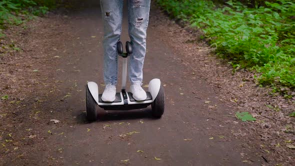 A Girl Dressed in Casual Rides Through the Forest on a Gyro Scooter