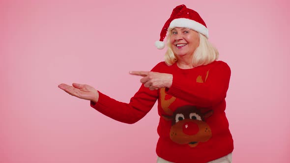 Grandmother in Santa Christmas Sweater Showing Thumbs Up and Pointing Empty Place Advertising Area