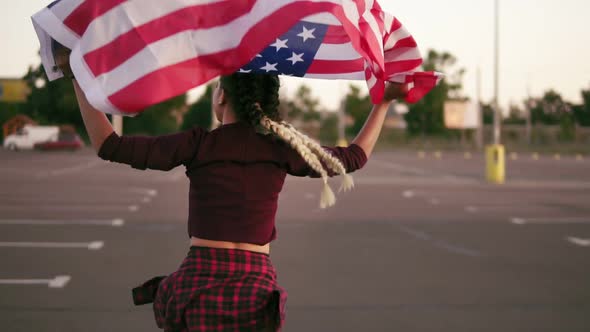Back View of a Young Happy American Girl Running While Holding the American Flag