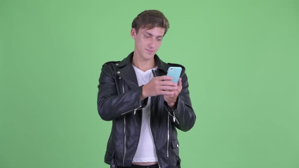 Happy Young Rebellious Man Thinking While Using Phone