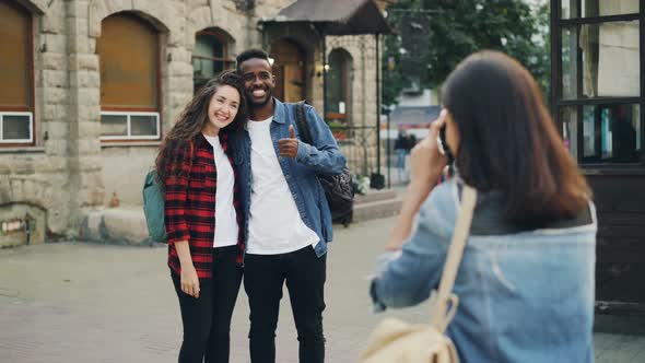 Young Woman Is Taking Pictures of Beautiful Couple African American Guy and Caucasian Girl Standing