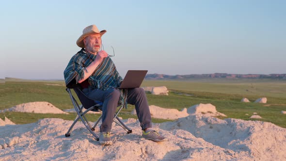 Senior man is working on laptop in the middle of nowhere