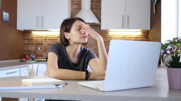 Tired Woman is Working on Laptop Computer at Home Office