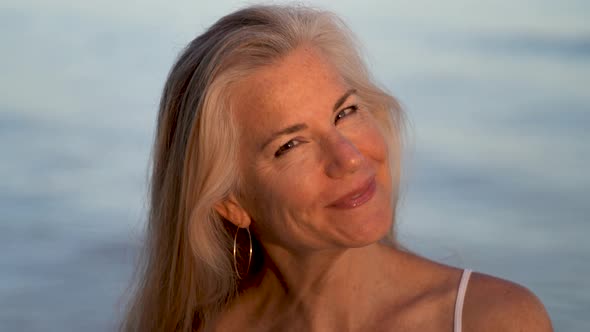 Blonde mature woman nodding yes while smiling and looking at camera.