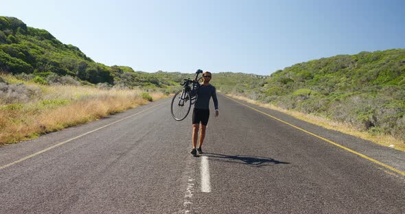 Triathlete man carrying cycle in the countryside road