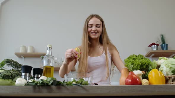 Vegan Girl Cooking Salad with Raw Vegetables, Adding Lemon Juice. Squeeze a Lemon Fruit in Hands