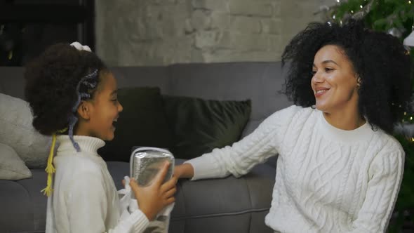 Portrait of African American Mom Surprises Her Little Daughter with a Gift