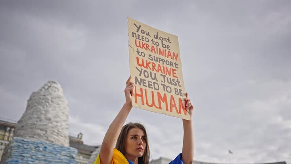 Woman Lifts Poster Against Cloudy Sky Calling for Support