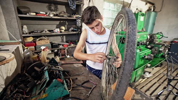 Teen Boy Screwing Bicycle Wheel