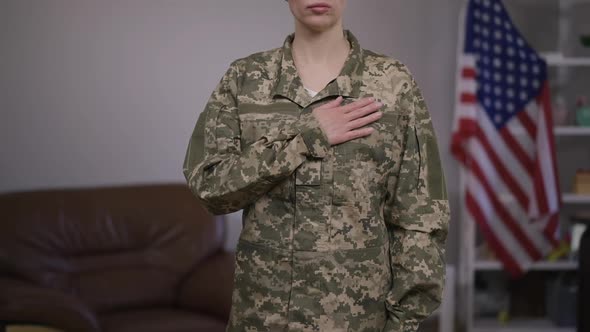 Unrecognizable Serious Military Woman in Camouflage Uniform Putting Hand on Chest Standing with USA