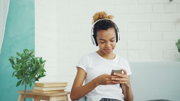 Pretty Young Woman Student Is Texting Friends Chatting Online and Listening To Music Through