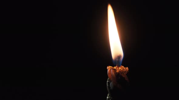 A Single Candle Is Lit on a Black Background. Candle Flame in the Dark.