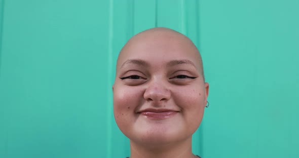 Bald girl posing and smiling in front of camera with colorful background