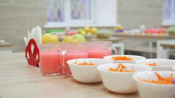 Carrot Salad and Glass Mugs with Juice on Table in Canteen