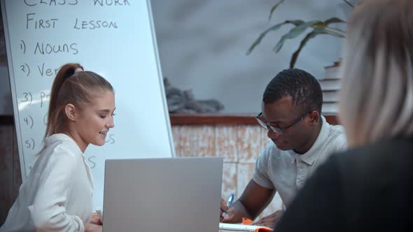 A White Woman and Black Man Having an English Lesson - the Teacher Watching Them