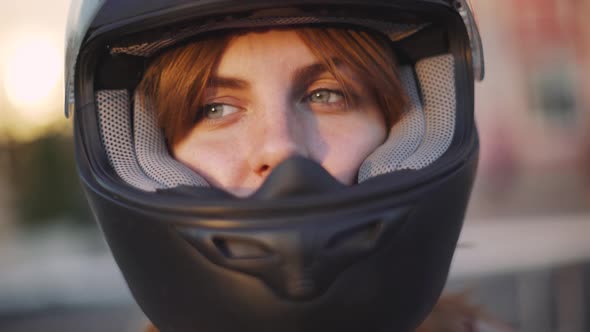 Portrait of Beautiful Young Redhaired Woman Motorcyclist in Helmet at Sunset