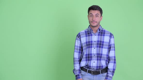 Stressed Young Hispanic Man Snapping Fingers and and Giving Thumbs Down