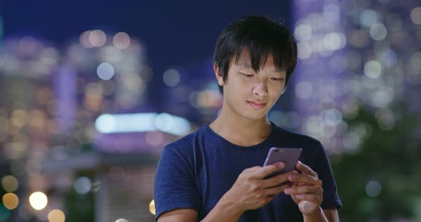 Young Man use of mobile phone in city at night