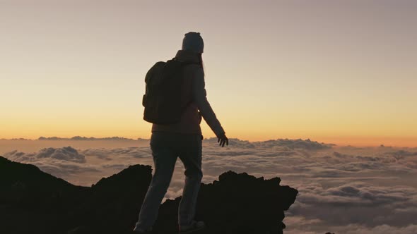 Cinematic Footage Above Pink Clouds  Traveler Walking Up Volcanic Peak Sunset