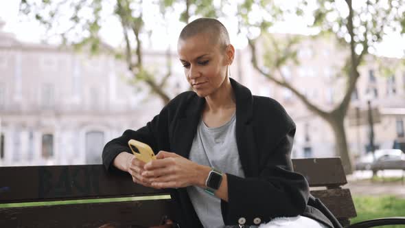 Pensive bald woman texting on phone