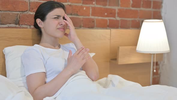 Young Indian Woman Feeling Worried while Sitting in Bed