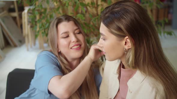 LGBT Women Sit Together in the Living Room Talk to Each Other Smiling and One of Them Touches Her