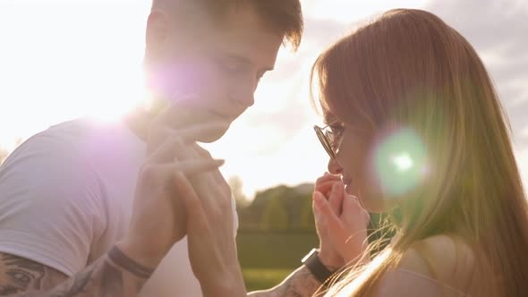 Close-up of a Girl in Sunglasses Hugging Her Boyfriend in a Park at Sunset.