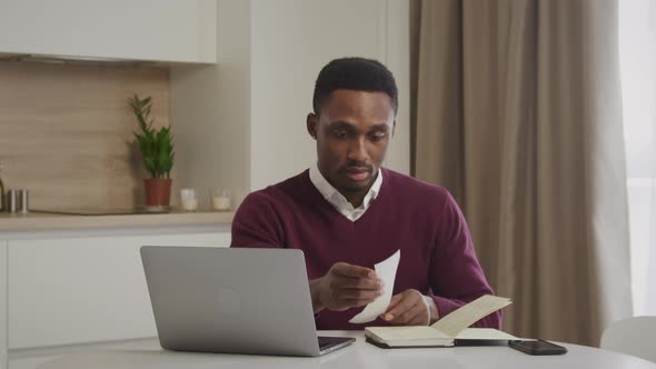 Young African American Man Checking Through His Bills and Managing the Household Expences