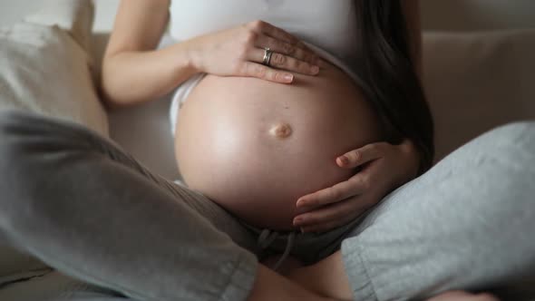 Close-up of the Pregnant Woman's Belly While She's Stroking and Touching It. Slow Motion Video