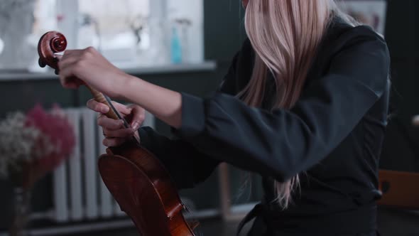 Young Blonde Woman Musician Tuning the Violin