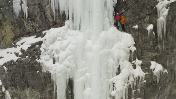 Climbers resting on ledge of frozen cascade ice climbing Maineline, Kineo Mount