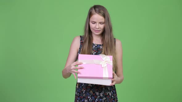 Young Beautiful Pregnant Woman Looking Surprised While Opening Gift Box