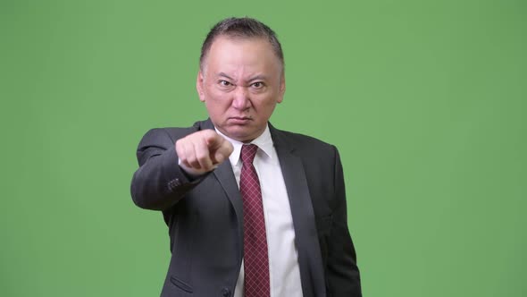 Mature Angry Japanese Businessman Pointing at Camera