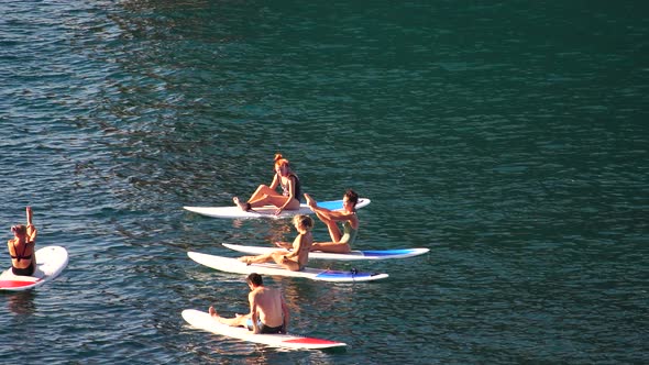 Group of Young Womens in Swimsuit Doing Yoga on Sup Board in Calm Sea Early Morning