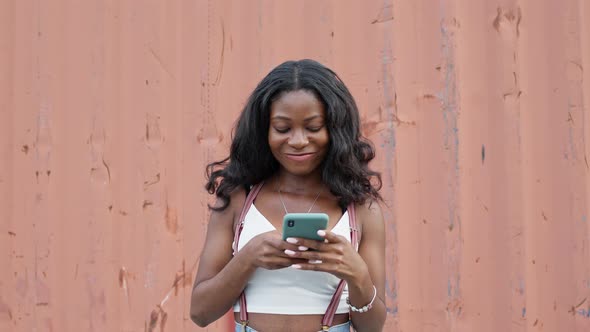 Cheerful Pretty Girl. Young Black Girl With Mobile Phone In Her Hands.