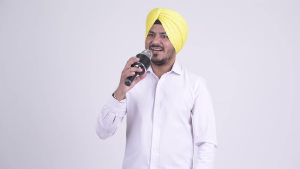 Happy Bearded Indian Sikh Businessman Singing with Microphone