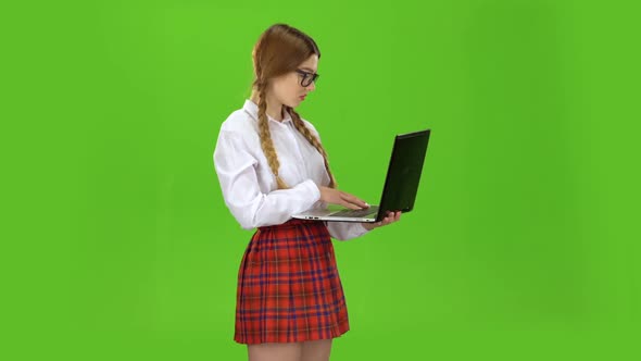 Student Holds a Laptop in Her Hands and Prints on the Keys. Green Screen