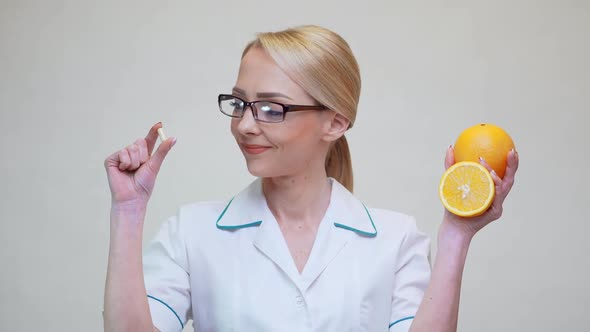 Nutritionist Doctor Healthy Lifestyle Concept - Holding Vitamin Pill and Orange Fruit
