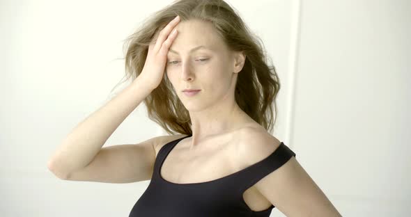 Emotional Female Model Is Touching Her Hair and Smiling in Front of Camera in Room