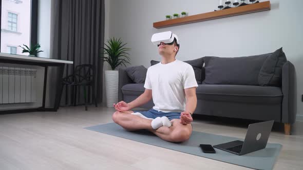 Cheerful Man in Virtual Reality Glasses Meditates in the Living Room Modern Technology and Augmented