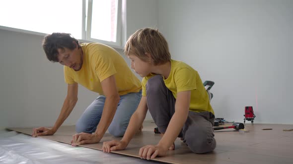 Father and His Little Son Install Laminate on the Floor in Their Apartment