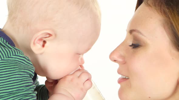 Mother Kissing Her Baby While He Plays. White. Close Up